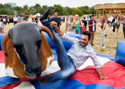 A boy fall off a mechanical bull at a summer party