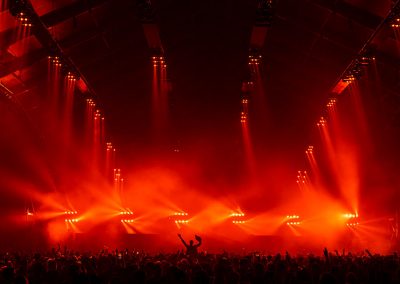 A single figure rides a packed crowd in a massive event arena all lit in red