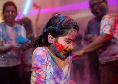 A young girl is coved in powder at a Diwali event