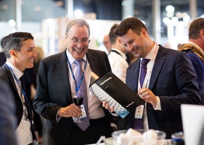 Happy businessmen at a London event look at a corporate brochure discussing plans
