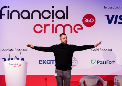 A man stand on a conference stage with his arms outstretched symbolising his business approach