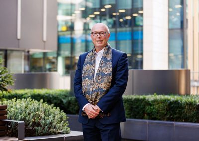 A CEO of a large London business poses in front of a London office for a company portrait