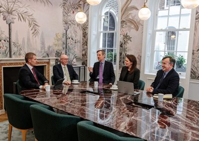 Corporate CEO’s sit at a marbled business table in a London office discussing strategy