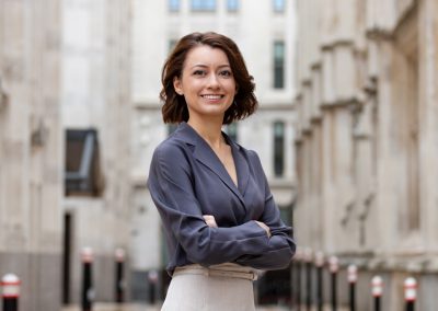 A young business lady stands between white London buildings posing for a company portrait